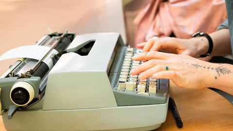 Close-up of Raisa's hands typing on a typewriter