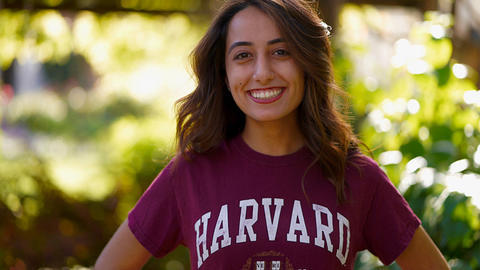Ciara Moezidis, MTS ‘23 in a crimson Harvard shirt in front of a blurred green background