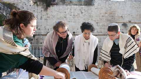A group of woemn reading the Torah in front of the Wall