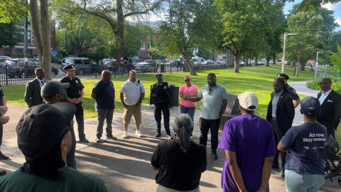 Kenneth Moales III, MDiv '24, gesturing in center of circle, speaks to attendees at a unity walk at Harambee Park in Boston this summer.