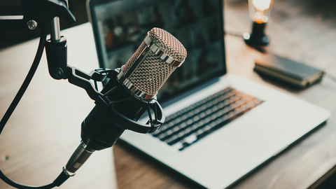A microphone in front of an open laptop on a desk
