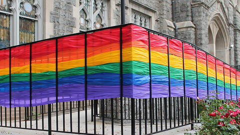 Rainbow banner woven into fence surrounding a church