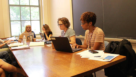 Four students in a classroom working on laptops