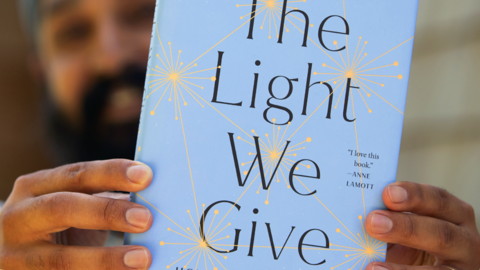 The Light We Give Book Cover held by Simran Jeet Singh in the background