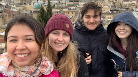 Group of students pose for a photo in front of city skyline.