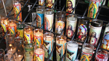 Rows of Christian votive candles with images of saints on them