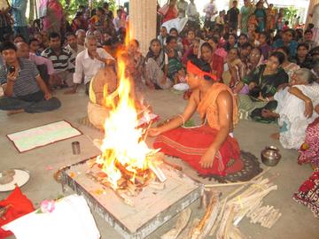 PArticipants light a flame at an in person puja