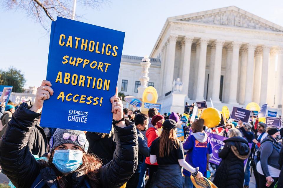 Woman holding sign in front of Supreme Court that reads "Catholics Support Abortion Access".