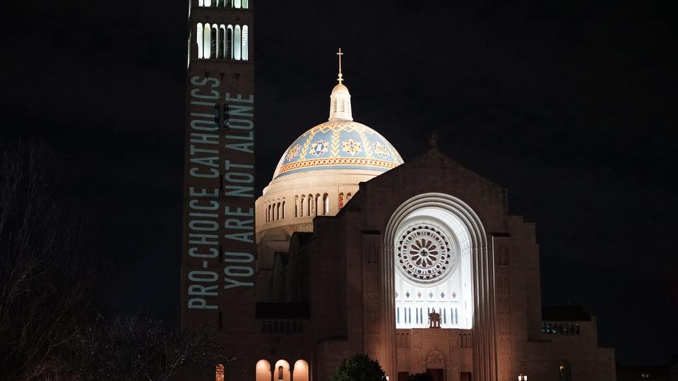 Words shining on bell tower at Catholic University of America that reads" Pro Choice Catholics You Are Not Alone.=