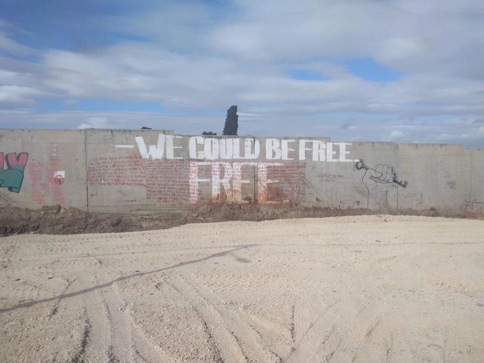 Wall in Israel/Palestine graffitied with an image of a hand clenched in a fist around a key and the words, 