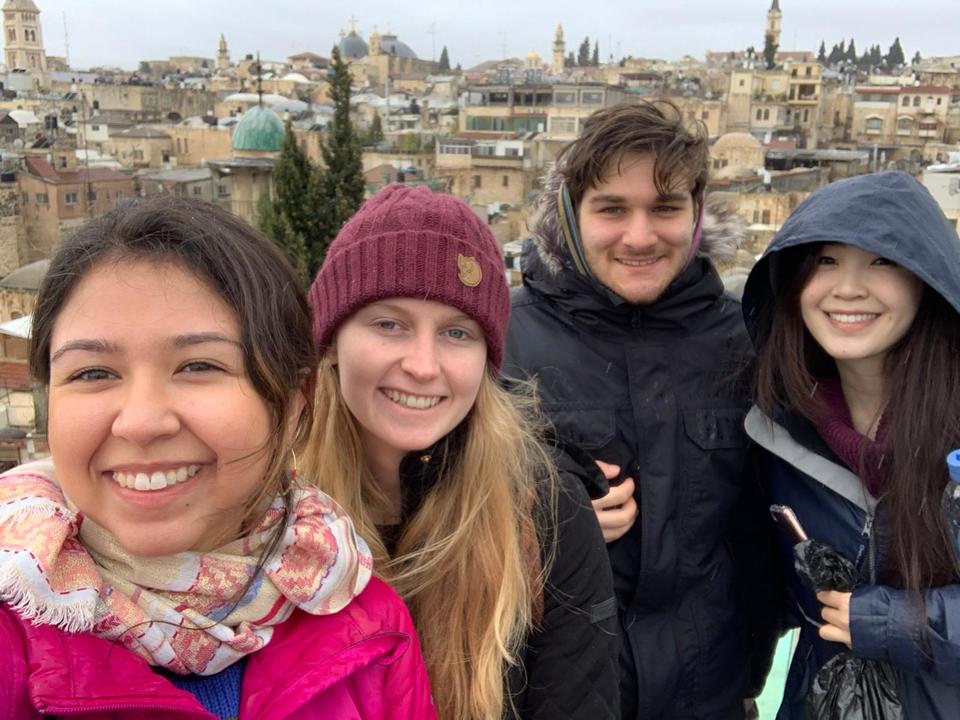 Group of students pose for a photo in front of city skyline.