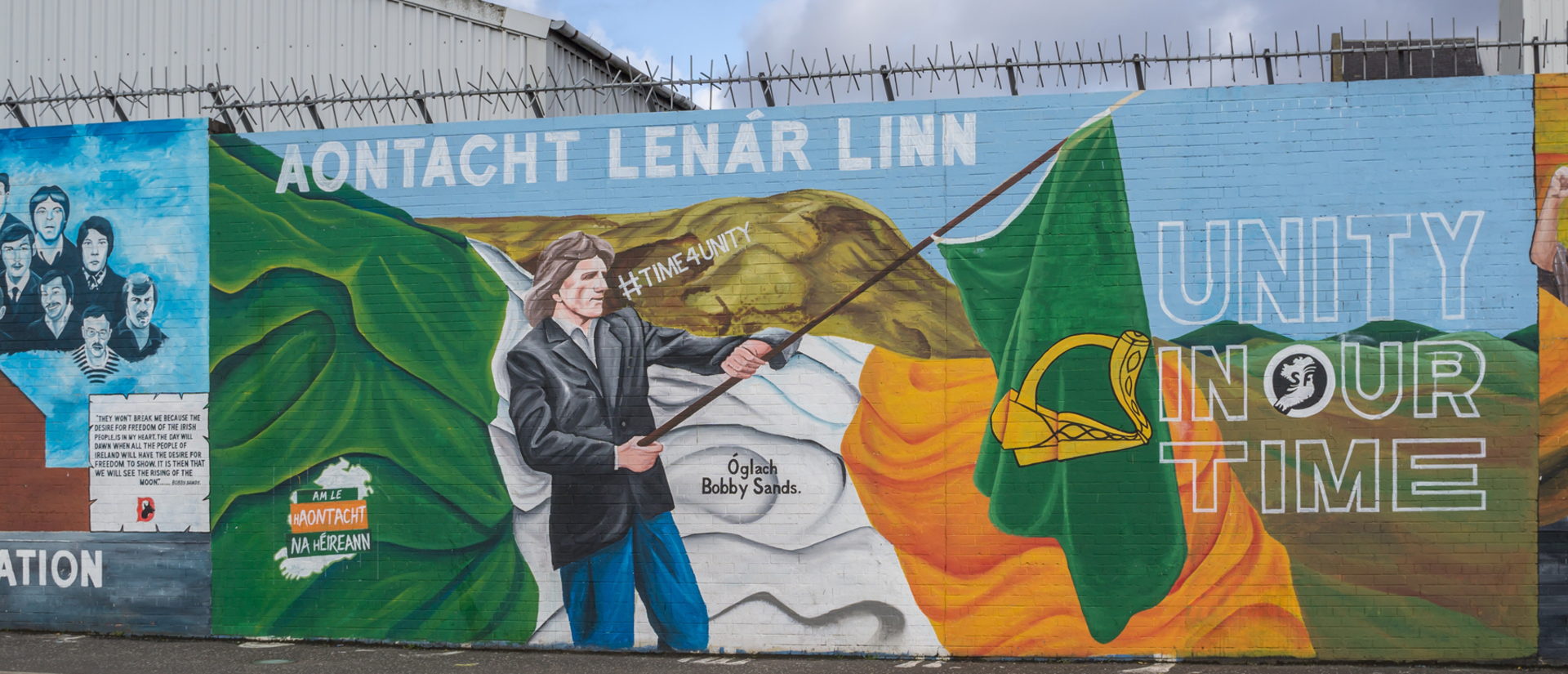 Mural in Belfast, Ireland of Bobby Sands carrying a green harp flag, symbol of Ireland and in particular of the United Irishmen, and marching under the #TimeForUnity message with the words "Aontacht Lenár Lınn" and "Unity in our time.